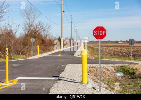 Pista ciclabile multiuso o multiuso con barriere stradali e segnale di stop. Percorso ferroviario, attività ricreative all'aperto e concetto di sicurezza pista ciclabile. Foto Stock