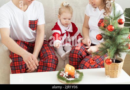 Bambina con impianto coclear divertirsi con la madre e il padre a casa - vacanze e diversità e concetto di assistenza all'udito Foto Stock