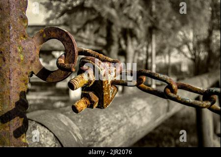 Dettaglio di un arrugginito catena e un lucchetto e corrosi dal tempo in una situazione con bassa molto triste e malinconico illuminazione. Foto Stock