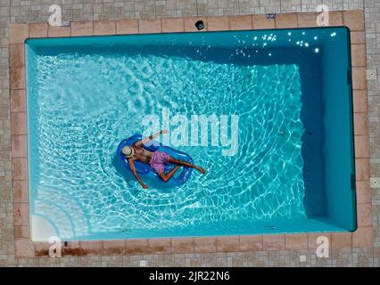 Uomo su un lilo in piscina Foto Stock