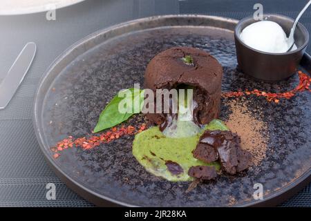 torta di lava. Fondente al cioccolato con ganache al basilico. Dessert tradizionale di cucina francese con ripieno d'autore. Foto Stock