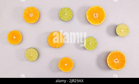 Creativa sistemazione estiva di lime di agrumi e arance su sfondo grigio. Giacitura piatta Foto Stock