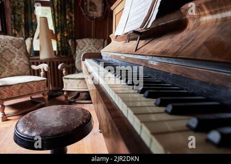 Primo piano di un pianoforte d'epoca con due antiche poltrone alle spalle Foto Stock