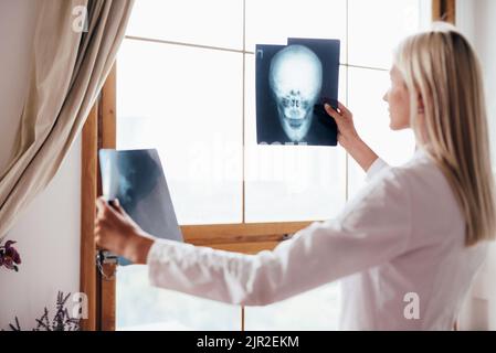 Medico di sesso femminile esamina le scansioni del cranio in ufficio. Foto Stock