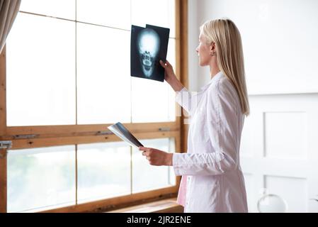 Il medico tiene i raggi X del cranio e lo guarda alla finestra. Foto Stock