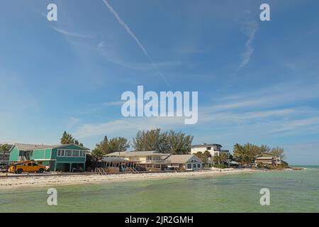 Skyline di case lungo la spiaggia a Bean Point, all'estremità nord di Anna Maria Island, Florida, con persone irriconoscibili che camminano sulla sabbia Foto Stock