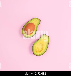 Sano avocado biologico con uova all'interno su fondo rosa pastello. Giacitura piatta Foto Stock