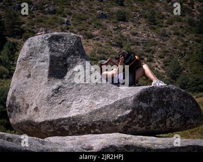 La padrona di cane gioca con il suo labrador Retriever al cioccolato su un masso di granito a forma di divano. Foto Stock