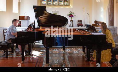 Due pianisti suonano grandiosi pianoforti in una Chiesa Foto Stock