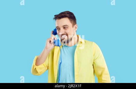 Un uomo sorridente parla al telefono fisso Foto Stock