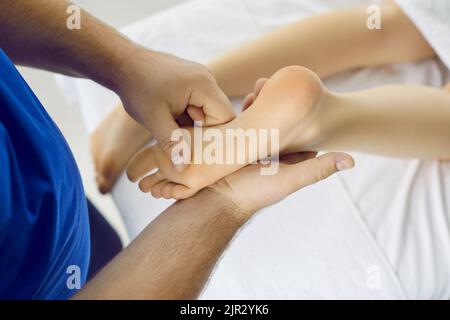 Riflessologo e terapia dell'acupressione professionista che fa massaggio del piede alla giovane donna Foto Stock