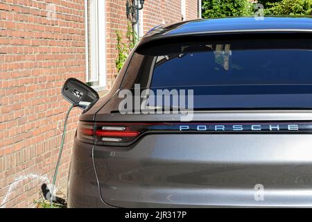 Veere, Paesi Bassi - Agosto 2022: Porsche auto elettrica collegata in un punto di ricarica fuori casa Foto Stock