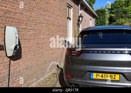 Veere, Paesi Bassi - Agosto 2022: Porsche auto elettrica collegata in un punto di ricarica fuori casa Foto Stock