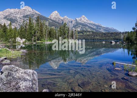 Le cime rocciose della catena del Teton si riflettono nelle acque ancora alpine del lago di Taggart Foto Stock