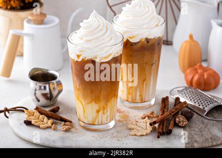 Latte speziato di zucca ghiacciato in bicchieri alti con panna montata Foto Stock