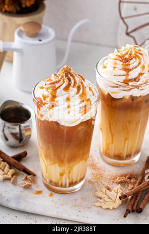Latte speziato di zucca ghiacciato in bicchieri alti con panna montata Foto Stock