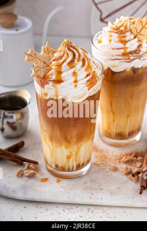Latte speziato di zucca ghiacciato in bicchieri alti con panna montata Foto Stock