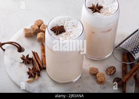 Latte di chai ghiacciato con spezie invernali calde sormontato da schiuma di latte Foto Stock