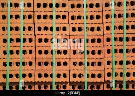 Mattoni rossi impilati legati con cinghie verdi. Foto Stock