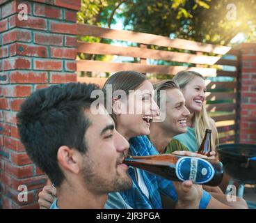 Che fine settimana senza buoni amici. Un gruppo di amici che hanno birre insieme ad un barbecue. Foto Stock