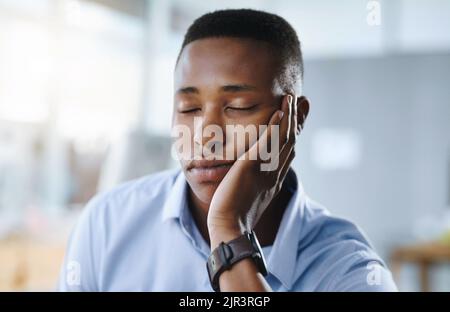 Non mi addormenterò, un uomo d'affari giovane e stanco che ha un rapido sonnellino con una mano in ufficio. Foto Stock