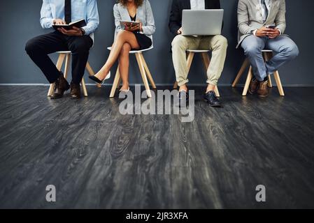 Preparandosi a mettere il loro piede migliore in avanti. Un gruppo di uomini d'affari irriconoscibili che aspettano in fila per un colloquio di lavoro. Foto Stock