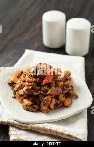 Mescolare le cozze di Fry con il peperoncino e la cipolla verde, il Mussel di stile asiatico. Primo piano di Tumis Kerang Foto Stock