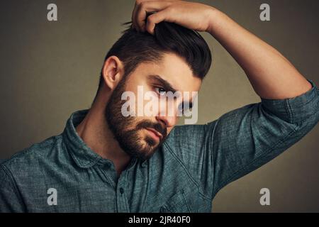 Non scegliete la barba la barba la sceglie voi. Studio shot di un bel giovane che si posa con la mano nei capelli. Foto Stock