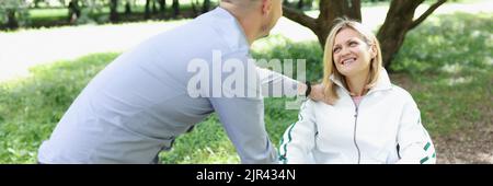 Il giovane comunica con la donna in sedia a rotelle Foto Stock