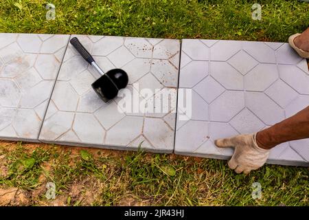 un lavoratore professionista posa lastre di pietra sul territorio di una casa di campagna. paesaggistica e paesaggio della zona Foto Stock