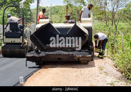 Uomini e asfalto macchina riparazione strada in Giamaica Foto Stock