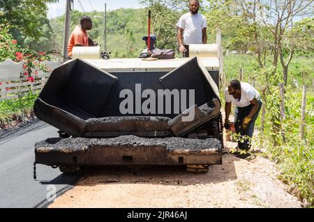 Uomini e asfalto macchina riparazione strada in Giamaica Foto Stock