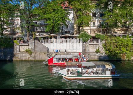 Lubiana, Slovenia - 13 luglio 2022: Tour in barca con turisti sul fiume Lubiana nel centro della città, crociera turistica sul fiume Foto Stock