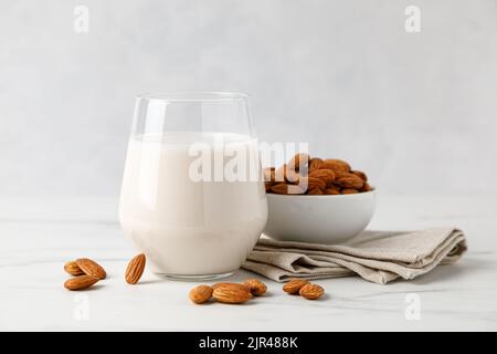 Latte di mandorla in un bicchiere e mandorle noci Foto Stock