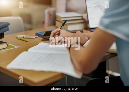 Primo piano dello studente si trova nella biblioteca, prepararsi per l'esame e prendere appunti nel notebook Foto Stock