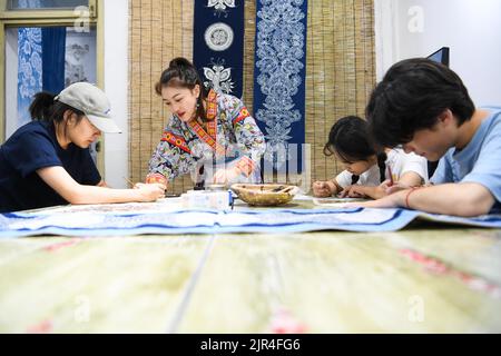 (220822) -- GUIYANG, 22 agosto 2022 (Xinhua) -- Zhang Juanjuan (2nd L) istruisce i suoi parenti ed amici a fare le pitture batik ad uno studio batik DIY in Anshun della provincia sudoccidentale di Guizhou della Cina, 18 agosto 2022. Zhang Juanjuan, una ragazza del gruppo etnico di Miao, ha deciso di tornare a casa per prendere il controllo dei suoi genitori affari relativi ai prodotti batik fare dopo la laurea. Batik è un patrimonio culturale immateriale nella sua città natale. Ha registrato il laboratorio di batik dei suoi genitori come una società d'arte batik, e ha fondato il suo studio batik DIY. Per espandere la propria attività, Zhang Juanjuan e i suoi colleghi hanno d Foto Stock