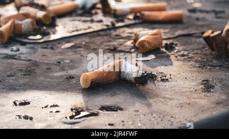 I mozziconi di sigaretta usati gettati sulla superficie sporca del posacenere Foto Stock