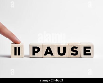 Il dito preme il pulsante di pausa sui cubetti di legno. Foto Stock