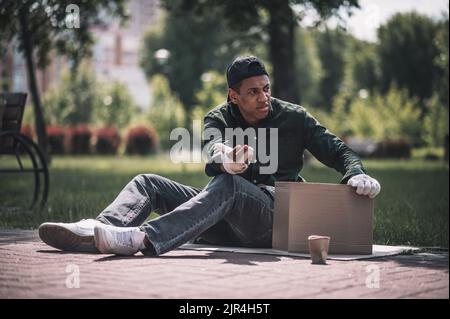 Uomo che guarda lontano seduto a terra Foto Stock