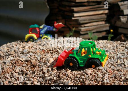 Trattori giocattolo su un mucchio di macerie, gioco per bambini Foto Stock