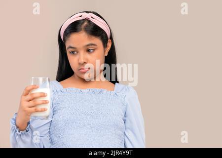 Ritratto di bambina che esprime infelicità su un bicchiere di latte in mano Foto Stock