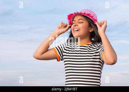 Ritratto di bambina con cappello contro il cielo blu in una giornata di sole Foto Stock