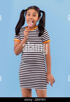 Ritratto di bambina lollipop leccando su sfondo semplice Foto Stock