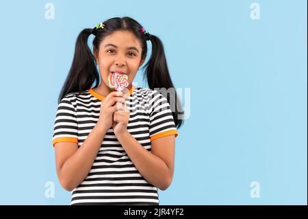 Ritratto di bambina lollipop leccando su sfondo semplice Foto Stock