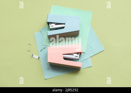 Cucitrici, note adesive e graffette su sfondo a colori Foto Stock