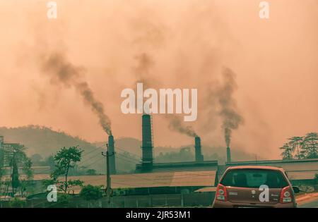 Fumo scuro come conseguenza di carbone che è bruciato in forni, che si sfugge da camini in una pianta di cemento in Byrnihat, Meghalaya, India. Foto Stock