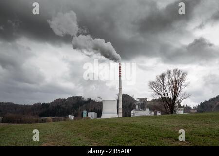 Torre di raffreddamento e camino di centrale termica con denso fumo bianco e grigio che sale nel cielo Foto Stock