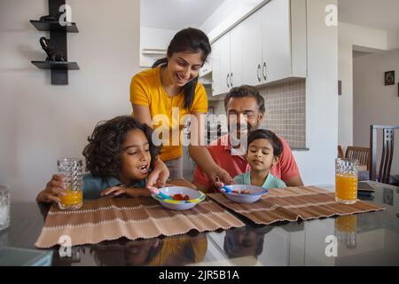 Ritratto di una famiglia nucleare al tavolo della colazione in soggiorno Foto Stock