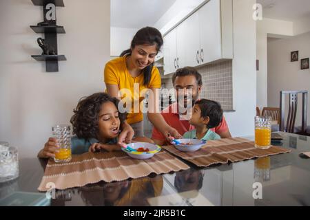 Ritratto di una famiglia nucleare al tavolo della colazione in soggiorno Foto Stock