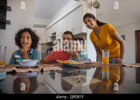 Ritratto di una famiglia nucleare che guarda via durante la colazione Foto Stock